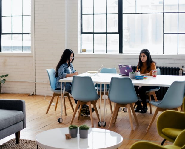 Two women working at a communal office table