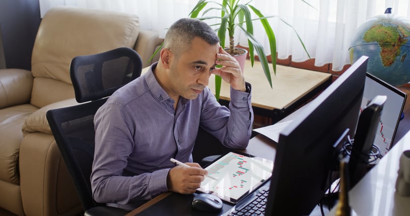 Worried businessman working in the office on stock market exchange data using desktop computer and digital tablet