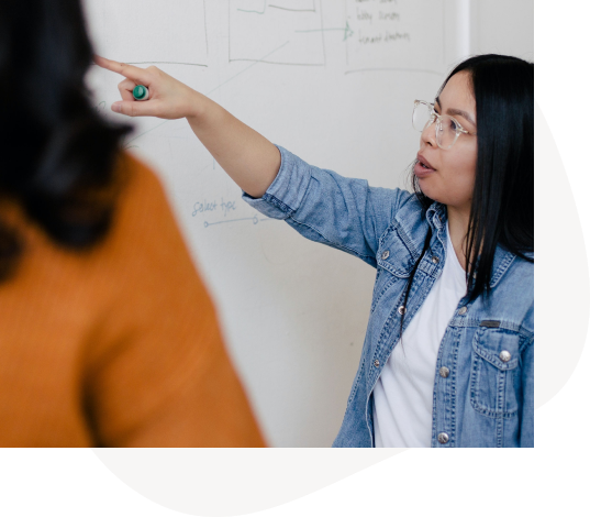 One woman explains a concept to another in the workplace.