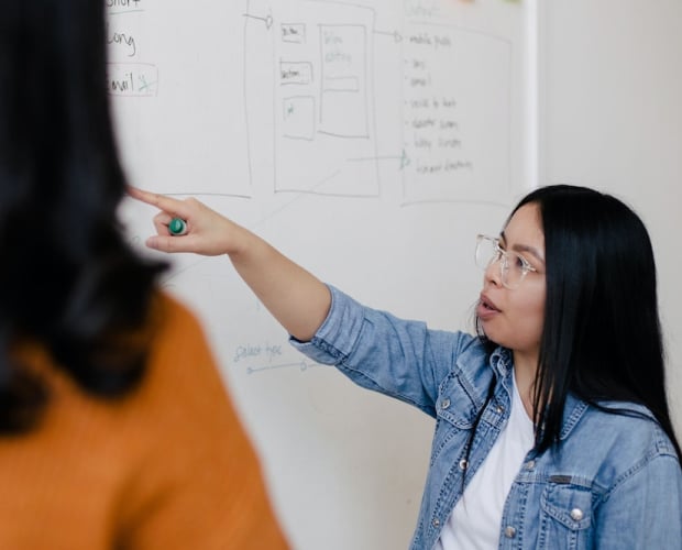One woman explains a concept to another in the workplace.