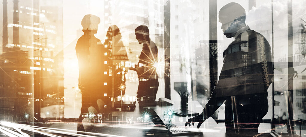silhouettes of professional men and women standing in a boardroom in conversation.