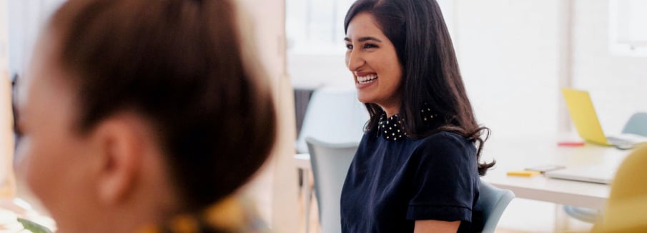 Two women smiling during a discussion in an office setting