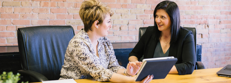 Two women referencing a tablet during a discussion